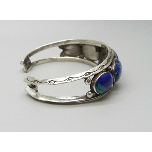 954 - A white metal bangle set with cabochon blue stones, 37g, largest stone 1.9 x 1.3cm