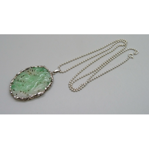 990 - A Chinese white metal mounted carved jadeite pendant on a silver chain, panel 4.2 x 2.8cm