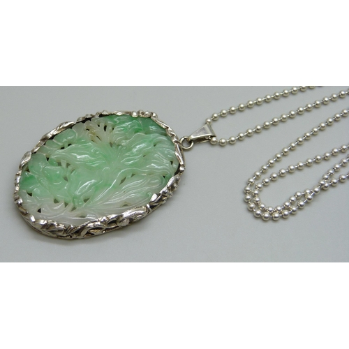 990 - A Chinese white metal mounted carved jadeite pendant on a silver chain, panel 4.2 x 2.8cm