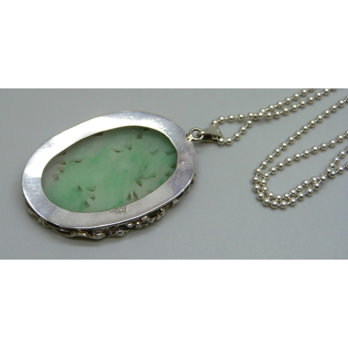 990 - A Chinese white metal mounted carved jadeite pendant on a silver chain, panel 4.2 x 2.8cm