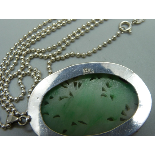 990 - A Chinese white metal mounted carved jadeite pendant on a silver chain, panel 4.2 x 2.8cm