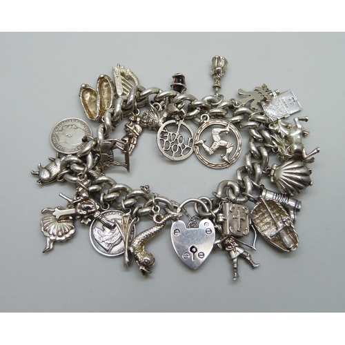 991 - A silver charm bracelet with a collection of silver, white metal and plated charms including a silve... 