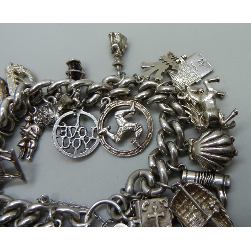 991 - A silver charm bracelet with a collection of silver, white metal and plated charms including a silve... 