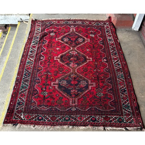 231 - A handmade Persian Shiraz red ground rug, 230 x 172cms