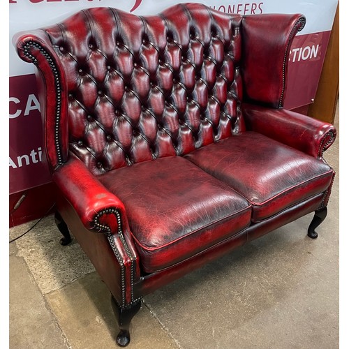 105 - An oxblood red leather Chesterfield wingback settee