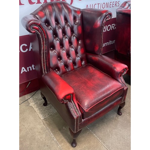 106 - An oxblood red leather Chesterfield wingback armchair