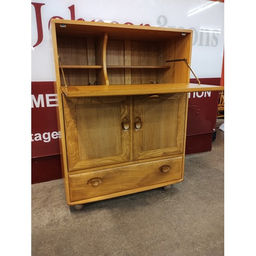 4 - An Ercol blonde elm Windsor writing cabinet