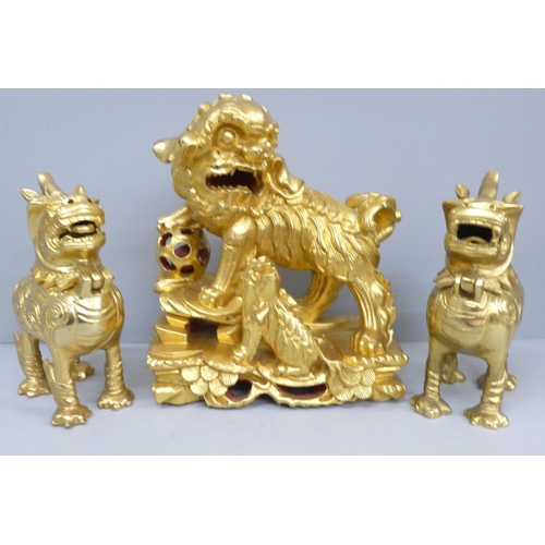 688 - A gilt wooden model of a temple dog and a pair of metal temple dogs with hinged heads