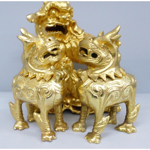 688 - A gilt wooden model of a temple dog and a pair of metal temple dogs with hinged heads