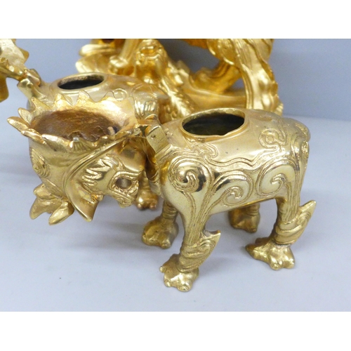 688 - A gilt wooden model of a temple dog and a pair of metal temple dogs with hinged heads