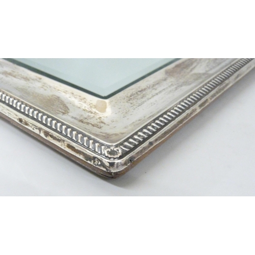 861 - A silver framed mirror with bevelled edge, with oak back, back stand requires repair, height 33.5cm