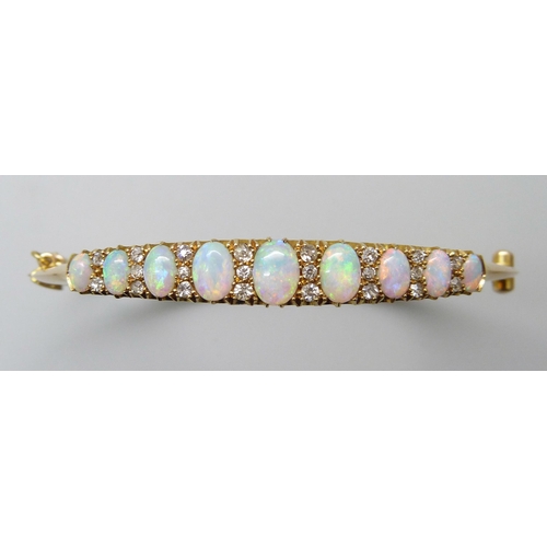 7043 - A 15ct gold opal and diamond bangle, 11.8g, central opal 0.7 x 0.5cm, 4.8 x 5.8 diameter