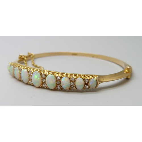 7043 - A 15ct gold opal and diamond bangle, 11.8g, central opal 0.7 x 0.5cm, 4.8 x 5.8 diameter