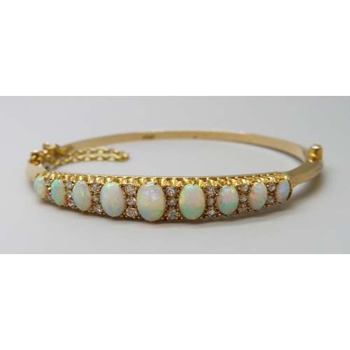 7043 - A 15ct gold opal and diamond bangle, 11.8g, central opal 0.7 x 0.5cm, 4.8 x 5.8 diameter