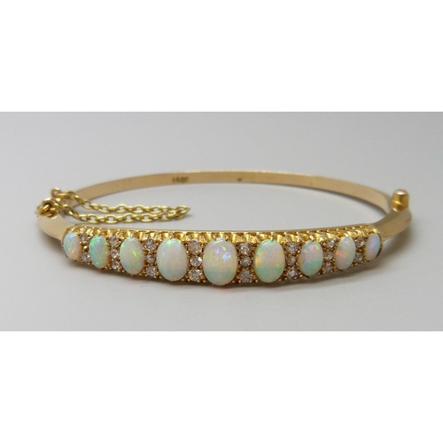 7043 - A 15ct gold opal and diamond bangle, 11.8g, central opal 0.7 x 0.5cm, 4.8 x 5.8 diameter