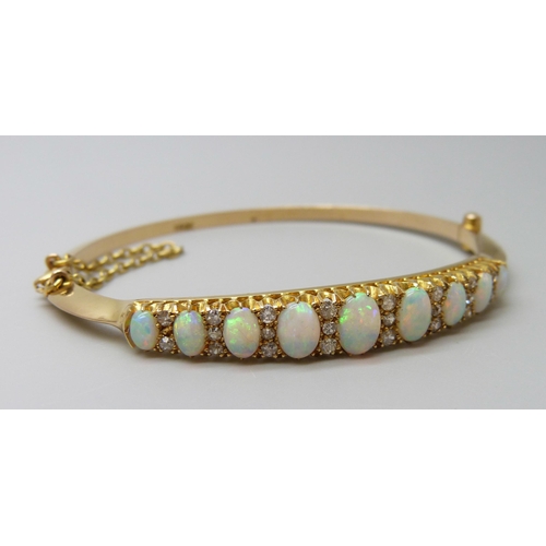 7043 - A 15ct gold opal and diamond bangle, 11.8g, central opal 0.7 x 0.5cm, 4.8 x 5.8 diameter