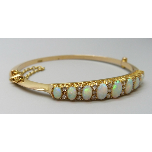 7043 - A 15ct gold opal and diamond bangle, 11.8g, central opal 0.7 x 0.5cm, 4.8 x 5.8 diameter