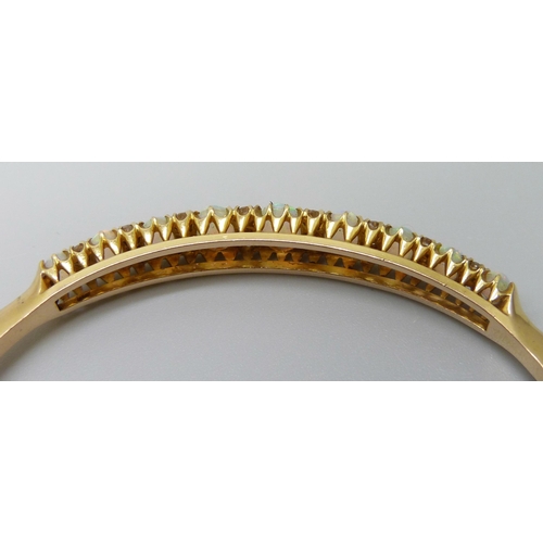 7043 - A 15ct gold opal and diamond bangle, 11.8g, central opal 0.7 x 0.5cm, 4.8 x 5.8 diameter