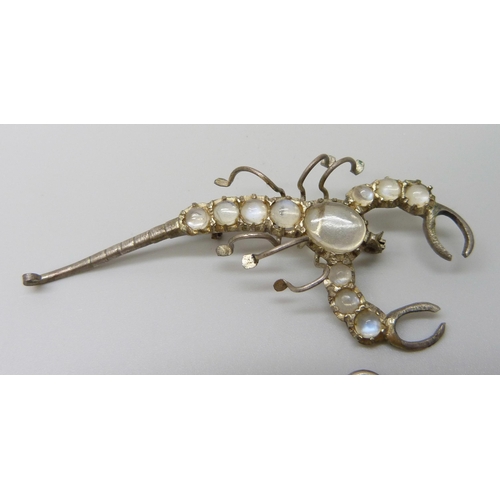 7104 - A white metal set moonstone scorpion brooch, 7.3cm, and other moonstone set jewellery parts