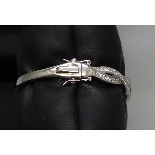 7133 - A silver twist bangle set with cubic Zirconia, 18.8g, band 0.7cm wide