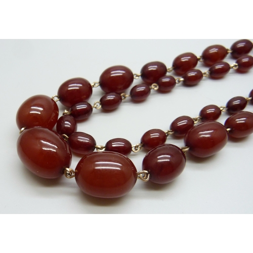 7146 - A two row sherry amber necklace, 54g, largest bead 2.2 x 1.6cm