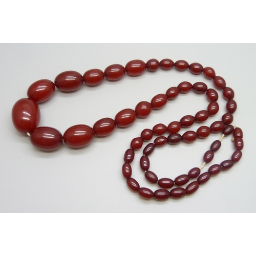 7147 - A sherry amber necklace, 65g, largest bead 2.8 x 1.9cm, two beads with swirl pattern