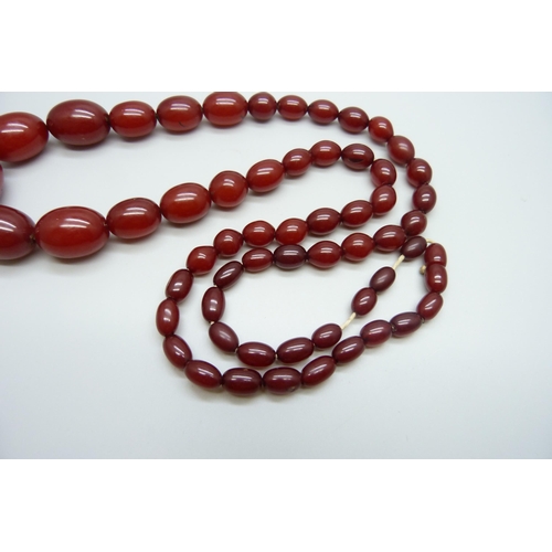 7147 - A sherry amber necklace, 65g, largest bead 2.8 x 1.9cm, two beads with swirl pattern