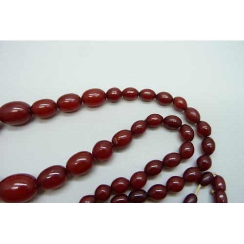 7147 - A sherry amber necklace, 65g, largest bead 2.8 x 1.9cm, two beads with swirl pattern