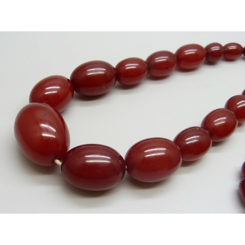 7147 - A sherry amber necklace, 65g, largest bead 2.8 x 1.9cm, two beads with swirl pattern