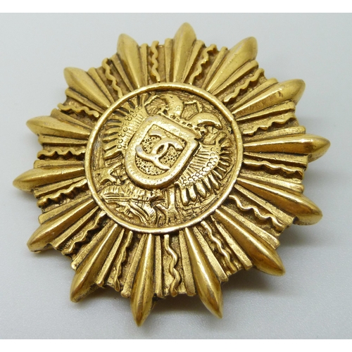 7150 - A Chanel gold tone CC logo sun shield brooch marked Chanel, made in France, 4.3cm