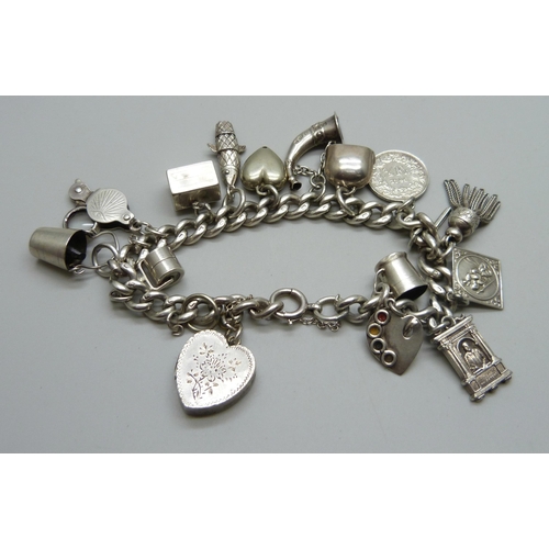 1019 - A silver charm bracelet with a collection of silver and white metal charms, 65g