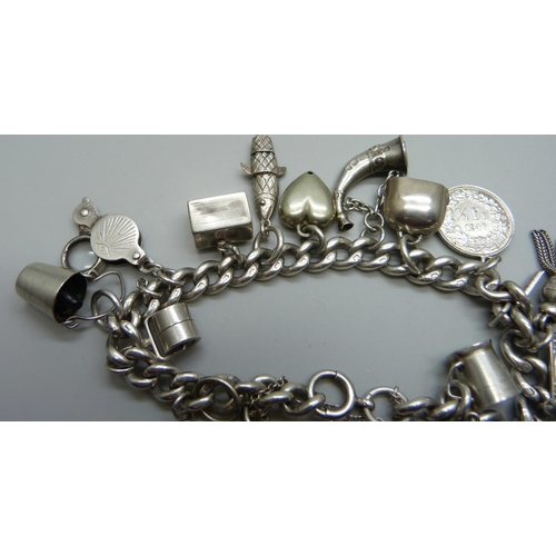 1019 - A silver charm bracelet with a collection of silver and white metal charms, 65g