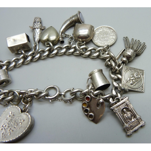 1019 - A silver charm bracelet with a collection of silver and white metal charms, 65g