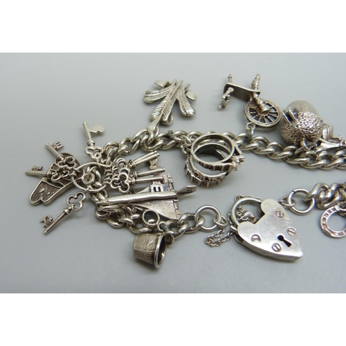 1061A - A silver charm bracelet with silver and white metal charms, 39g