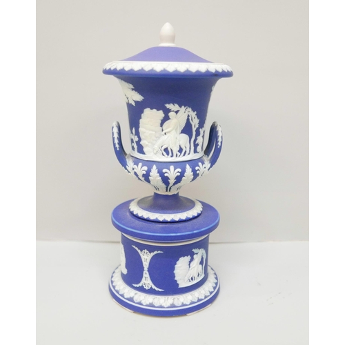 614 - A Wedgwood dark blue jasper twin handled urn with cover on a circular stand, 19cm