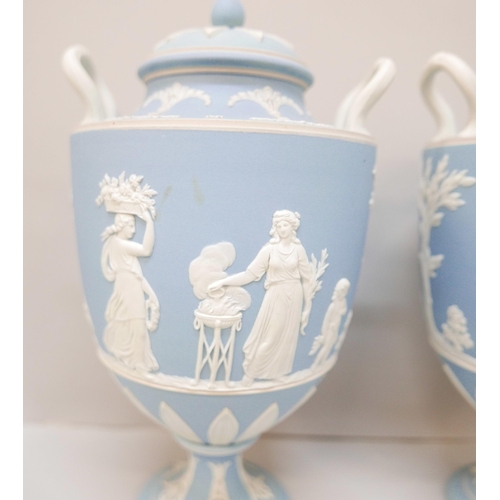 617 - A pair of Wedgwood blue jasper twin handled urns with covers, 24.5cm