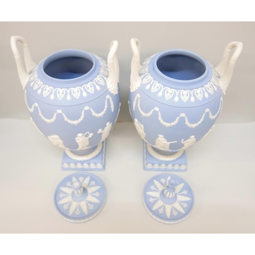 620 - A pair of Wedgwood blue jasper twin handled urns and covers (finals on covers not identical), 31cm, ... 