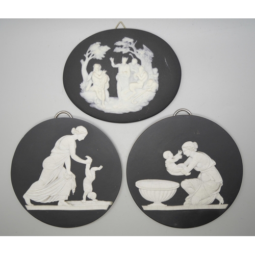 626 - A pair of Wedgwood black and white circular plaques and an oval plaque, each with classical scenes