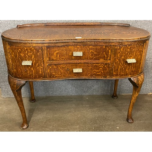 146 - An early 20th Century oak kidney shaped sideboard with bakelite handles