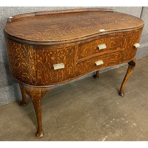 146 - An early 20th Century oak kidney shaped sideboard with bakelite handles