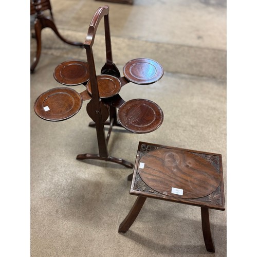 137 - An Arts & Crafts carved elm stool and an early 20th Century mahogany folding cake stand