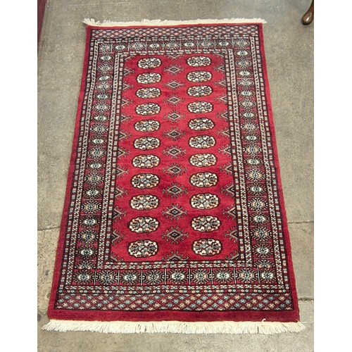 172 - A Bokhara hand knotted red ground rug, 94 x 161cms