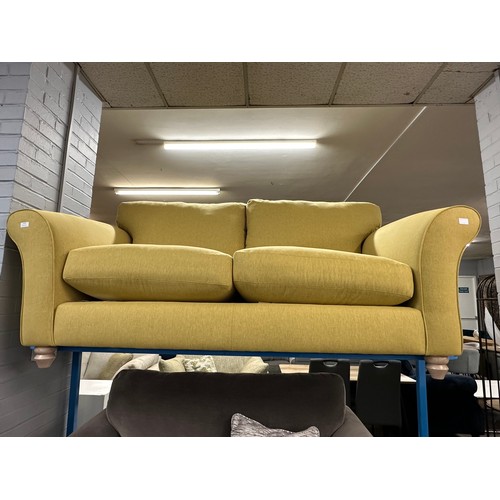 3110 - A bumblebee yellow upholstered two seater sofa on turned oak legs