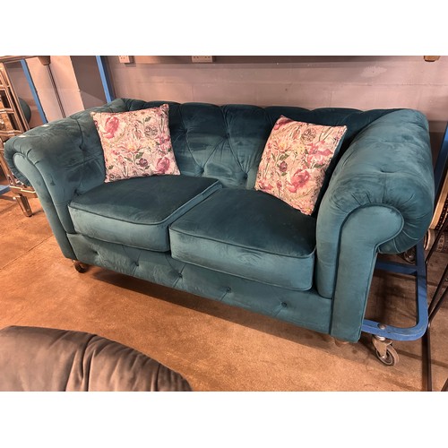 3022 - A turquoise velvet upholstered Chesterfield two seater sofa with patterned scatter cushions on turne... 