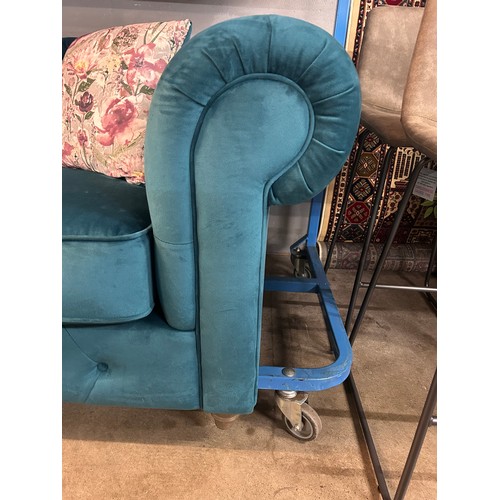 3022 - A turquoise velvet upholstered Chesterfield two seater sofa with patterned scatter cushions on turne... 