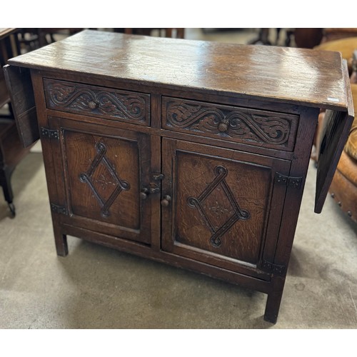 133 - A 17th century style carved oak drop-leaf credence cupboard