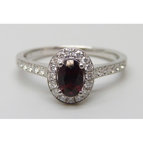 7065 - A platinum ring with an oval garnet surrounded with brilliant cut diamonds, diamond set shoulders an... 