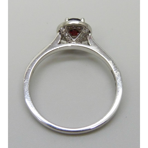 7065 - A platinum ring with an oval garnet surrounded with brilliant cut diamonds, diamond set shoulders an... 