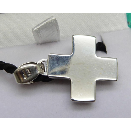 7086 - An 18ct white gold cross pendant set with 0.10ct diamond on a black cord with silver fastener, cross... 