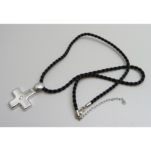 7086 - An 18ct white gold cross pendant set with 0.10ct diamond on a black cord with silver fastener, cross... 